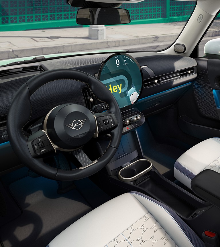 Interior de um MINI Cooper, com volante, bancos dianteiros e ecrã central circular  visíveis 